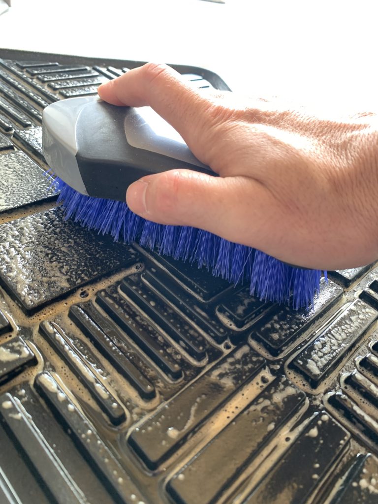 Scrubbing floor mats treated with Blitz with an upholstery brush