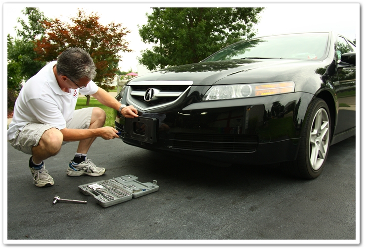 Removing the front license plate on an Acura TL prior to washing.