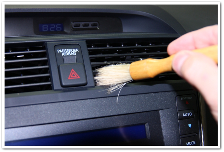 Cleaning tight areas of an interior of a 2006 Acura TL with a soft bristle brush